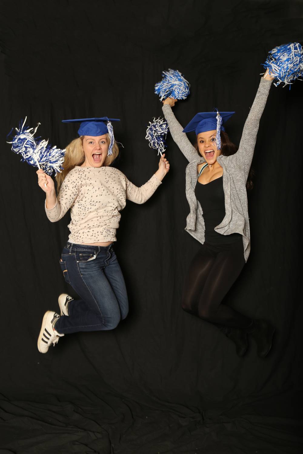two friends jumping with pom poms